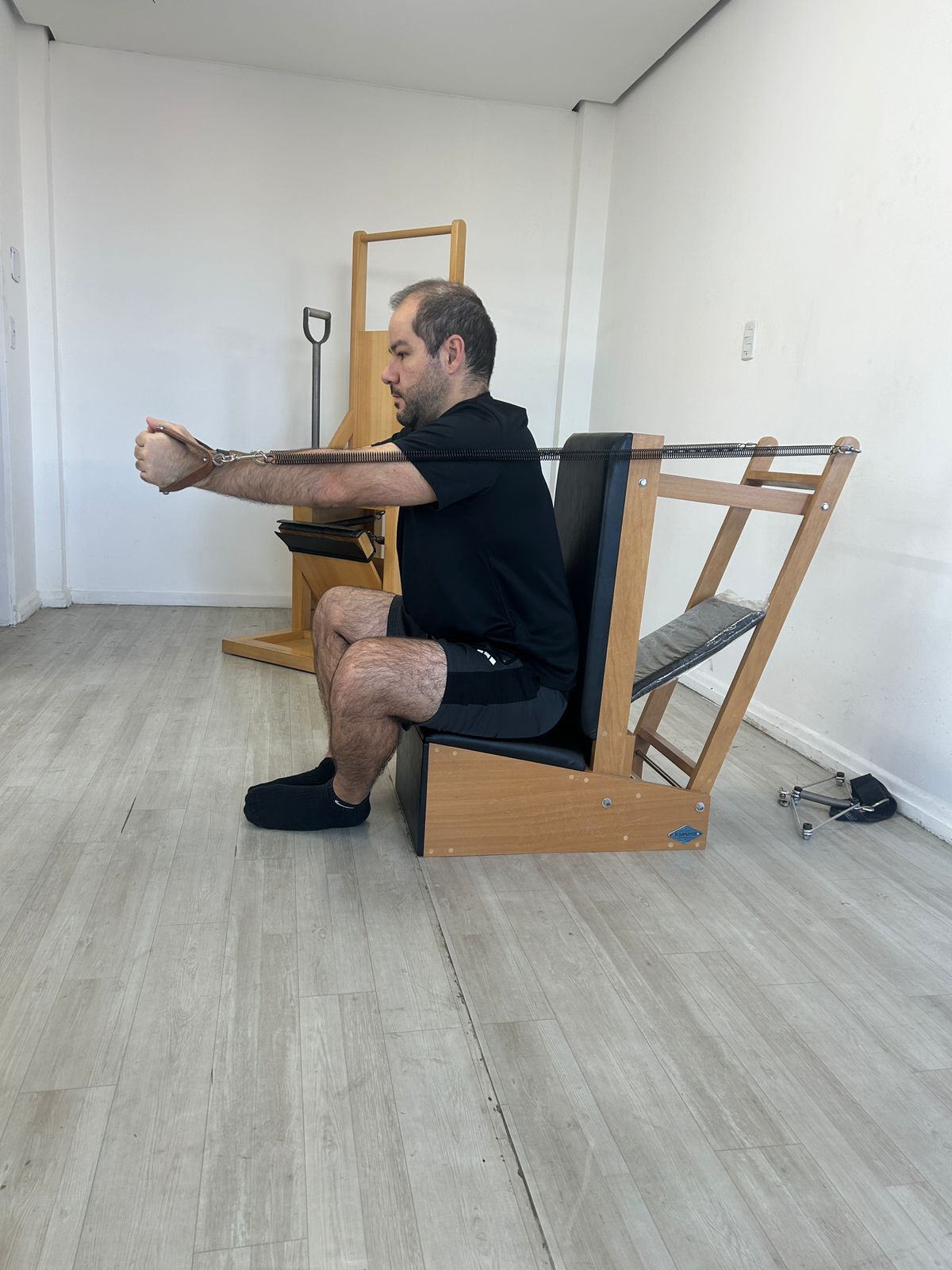 Aluno em exercício no Pilates Chair com molas.