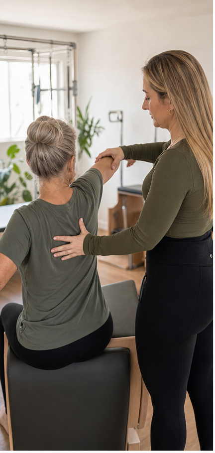 Fisioterapeuta acompanhando idosa em exercício de Pilates.